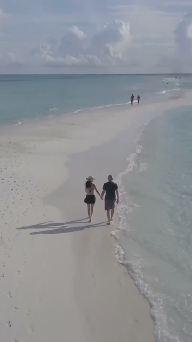 Pareja caminando por la playa al atardecer
